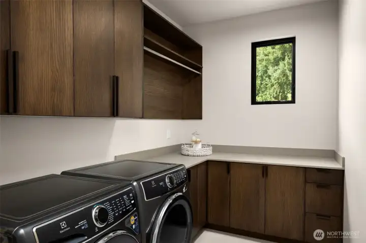 Spacious upstairs laundry room with built in cabinetry and expansive counter and storage space. Electrolux washer and dryer.