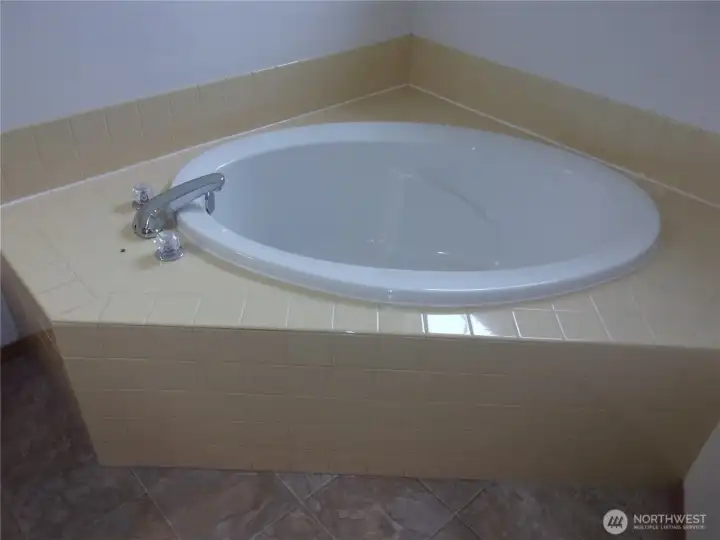 Tiled soaking tub in primary bathroom.