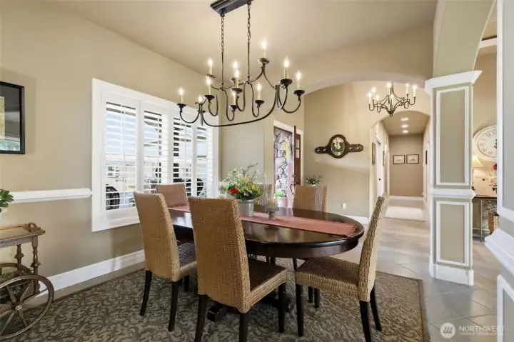Elegant formal dining room centered around a classic black wrought iron chandelier with curved arms and dimmable candle-style lighting.