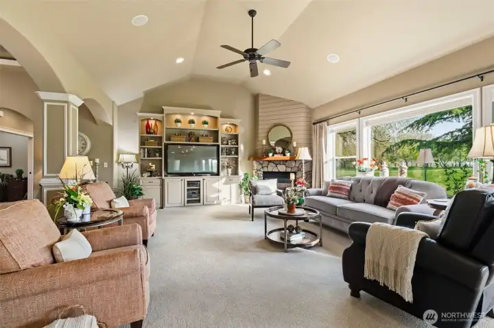 Spacious living room featuring a custom-built entertainment center and vaulted ceilings.