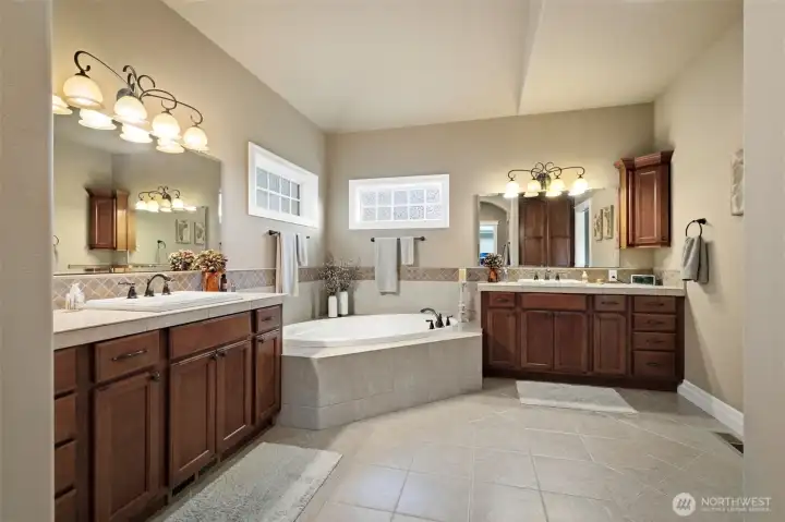 Spacious primary bath featuring separated dual vanities and soaking tub.