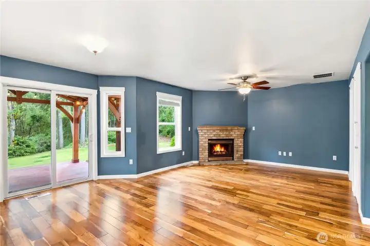 Bright living room featuring hardwood floors, gas fireplace, and large windows.
