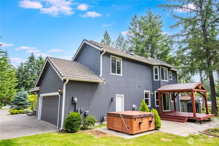 Backyard view featuring covered deck and hot tub area.