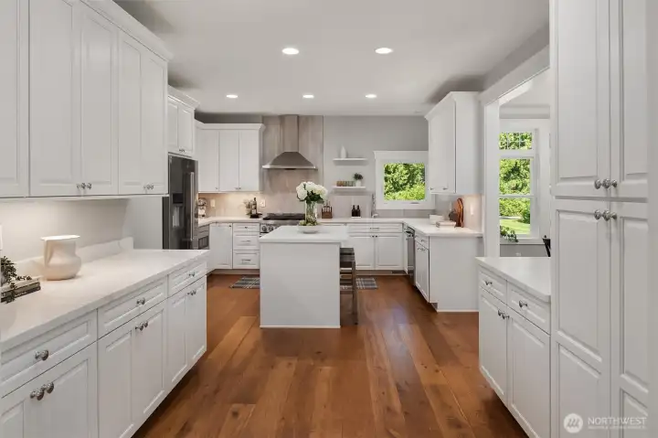 Updated chef's kitchen featuring quartz countertops, custom cabinetry, premium appliances, oversized island, and abundant prep space.