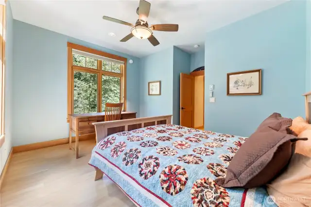 Main floor bedroom with lovely natural light, peaceful garden views, and private access to the adjacent full bath.