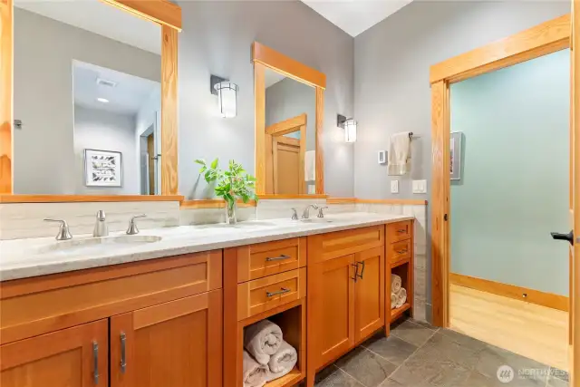 Elegant primary bath features dual sinks, slab stone counters, custom cabinetry, radiant heated floors, and soft modern lighting, lots of storage.