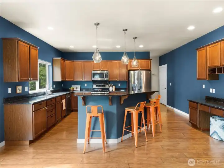 Large kitchen with slab granite counters, breakfast bar, stainless appliances and work station.