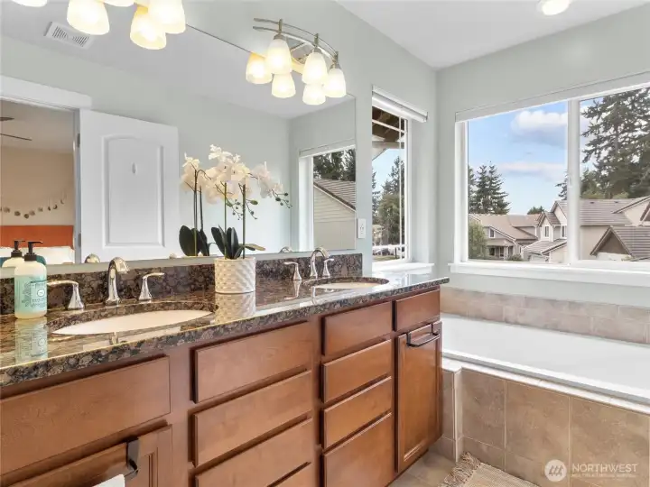 Granite countertops, tile flooring and large tub in the primary bathroom.