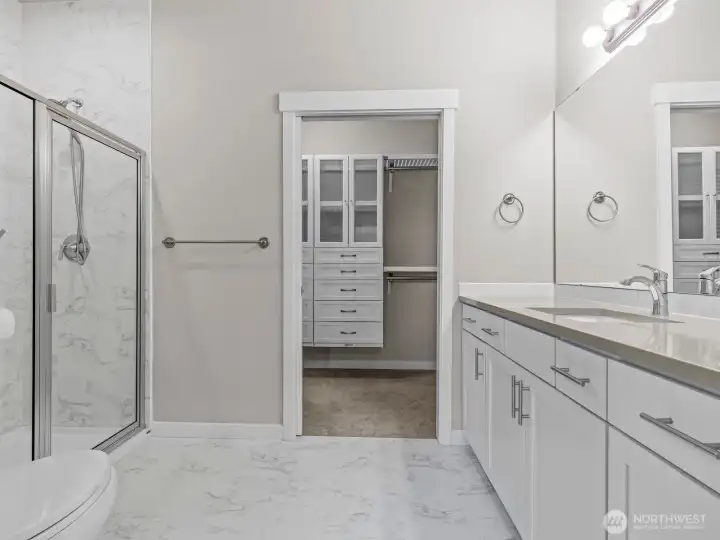 Gorgeous tile flooring continues up the walls of the shower and is accented by gorgeous quartz on the vanity.