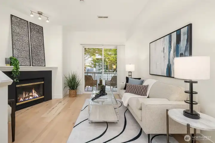 Open living room featuring hardwood floors, gas fireplace, and sliding door to private balcony.