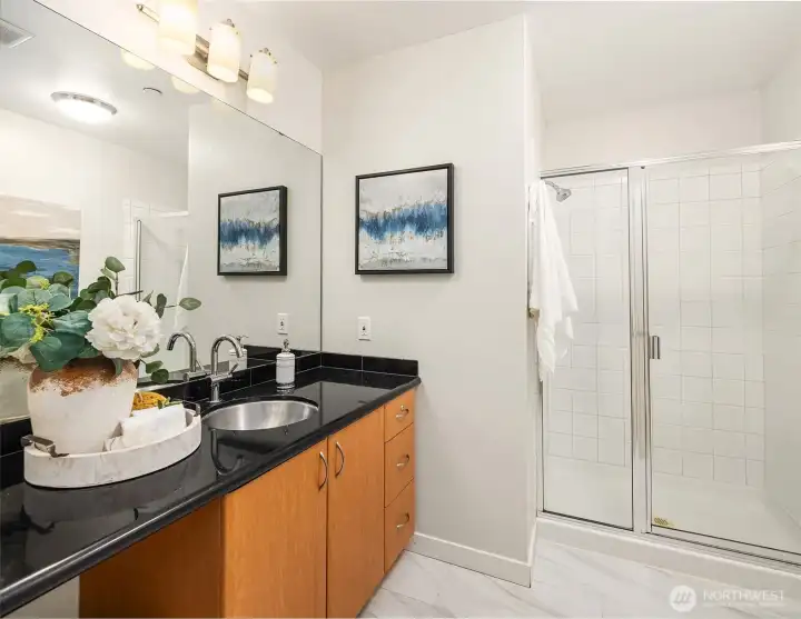 Primary bathroom with extended vanity, solid surface countertops, and walk-in shower with glass doors.
