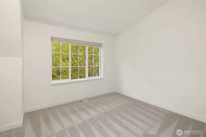 Secondary bedroom with plush carpet, large window, and flexible use for guests or office.