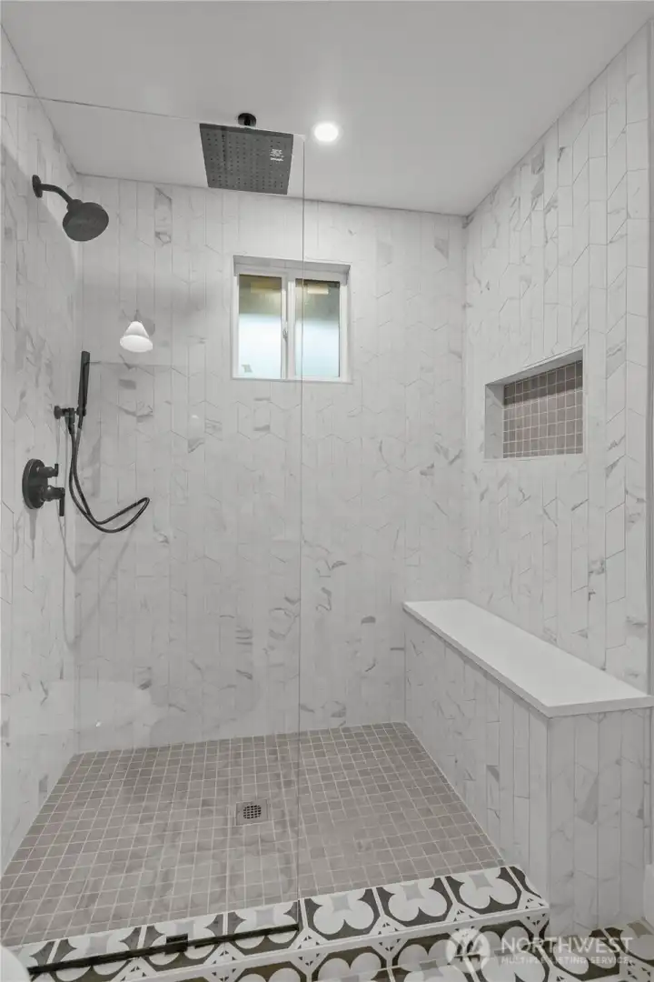 Spa-inspired main-level primary ensuite featuring a walk-in shower with bench seating, oversized rain shower, and timeless tilework—designed for daily comfort and long-term livability.