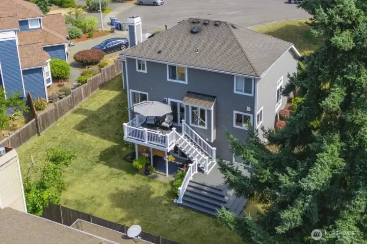 Aerial view showcasing the home, outdoor living spaces, and fully fenced backyard.