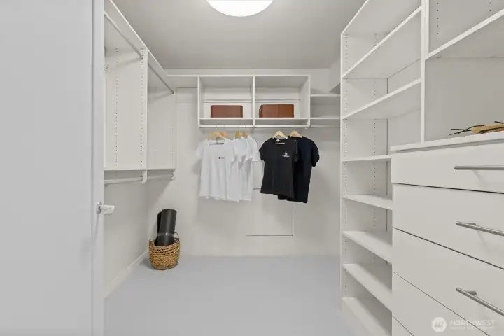 Walk-in primary closet with custom organizers. Walk-in primary closet with custom organizers.