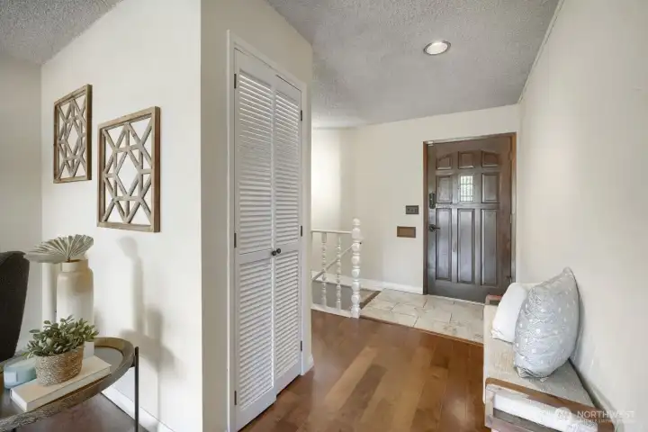 Welcoming Entryway with Warm Finishes    Step into a bright and inviting entryway featuring rich hardwood floors and a classic wood front door that adds warmth and character. The space offers a convenient coat closet and tasteful wall décor, creating a refined first impression. Natural light and neutral tones enhance the open feel, seamlessly connecting to the main living areas for a smooth, welcoming flow throughout the home.