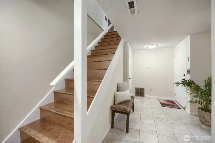 Lower-Level Entry with Heated Floors and Garage Access    This inviting lower-level entry features heated tile floors for year-round comfort and a clean, modern aesthetic. A wood-trimmed staircase leads to the main living area, while this level provides convenient access to a bedroom, bathroom, laundry area, storage space, and a spacious two-car garage. The streamlined layout offers both practicality and a warm welcome as you transition between levels.