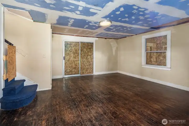 View from front door. Note: all windows and exterior doors are boarded up to ensure security while vacant. Living room looks out slider to large deck. View from front door. Note: all windows and exterior doors are boarded up to ensure security while vacant. Living room looks out slider to large deck.