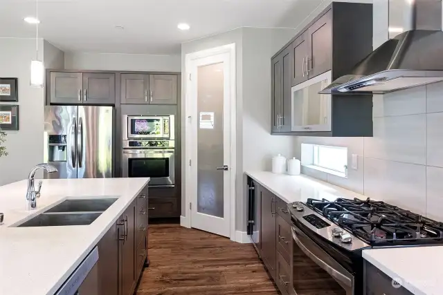 Kitchen with gas range, stainless appliances and wine fridge.