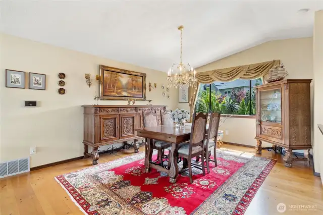 Formal dining room featuring vaulted ceilings and large window.