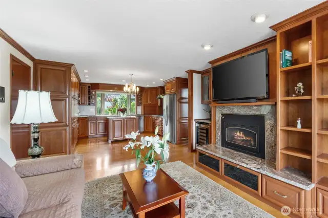The family room with gas fireplace, wine/beverage refrigerator center, built in wood shelves and is conveniently adjacent to the impressive kitchen.