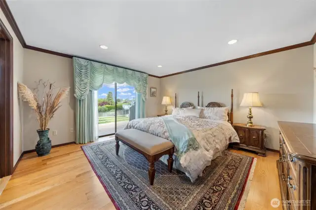 The primary suite on the main level features a spacious walk-in tile shower, dual sinks, granite countertops, a custom-designed closet, sophisticated wood cabinetry, and a large window that fills the space with ample light.