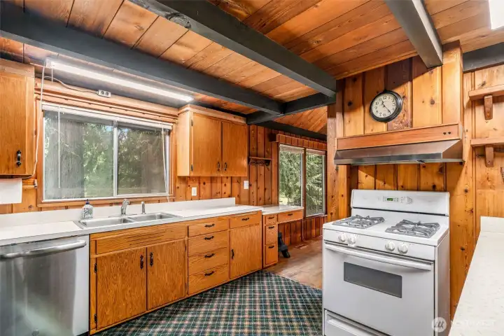 Straight on, the kitchen greets you with sturdy beams overhead and some newer appliances. The counters and cabinets are ready for a refresh, and yes—that carpet has definitely overstayed its welcome. But beneath it all, you can feel the bones of a space just waiting for its next chapter.
