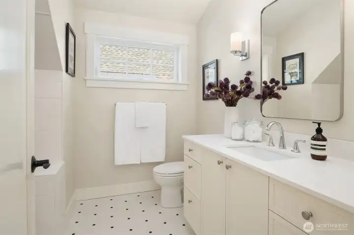 A large upstairs bath with tub features custom patterned tile and is shared by the two upstairs bedrooms.