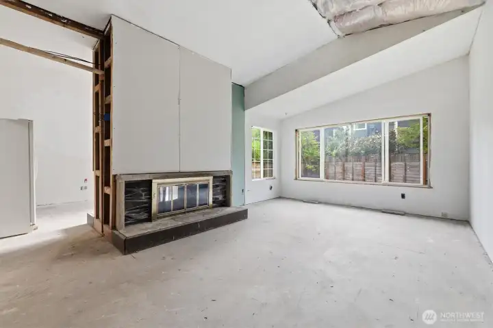 The vaulted living room with large vinyl windows overlooking the backyard.