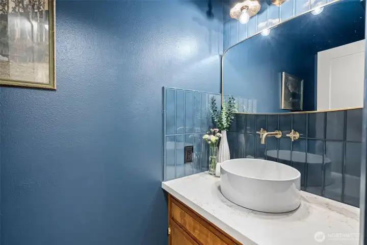 This moody half-bath is complete with a matte black toilet and gold fixtures.