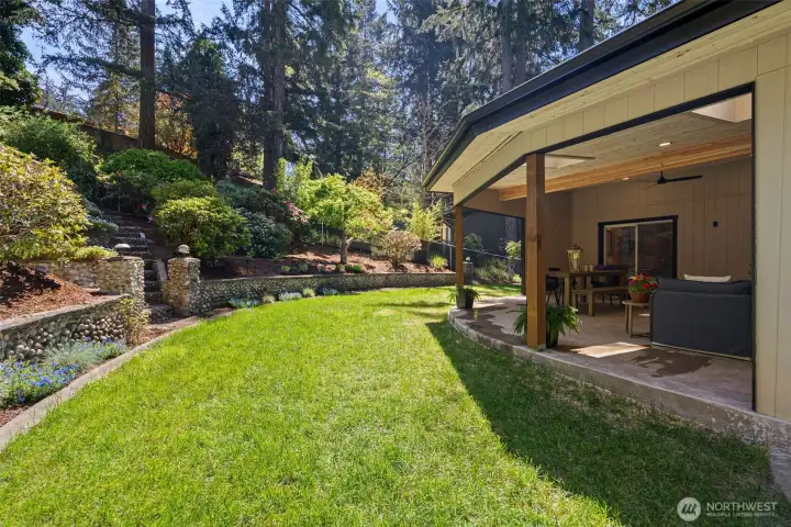 Tiered yard with mature landscaping and idyllic greenery provides a peaceful and private setting.