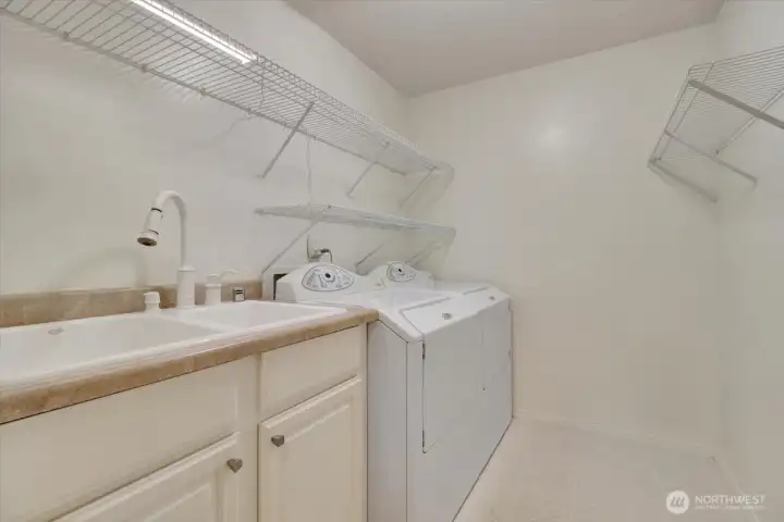 Full utility room with washer/dryer and sink with ample shelving