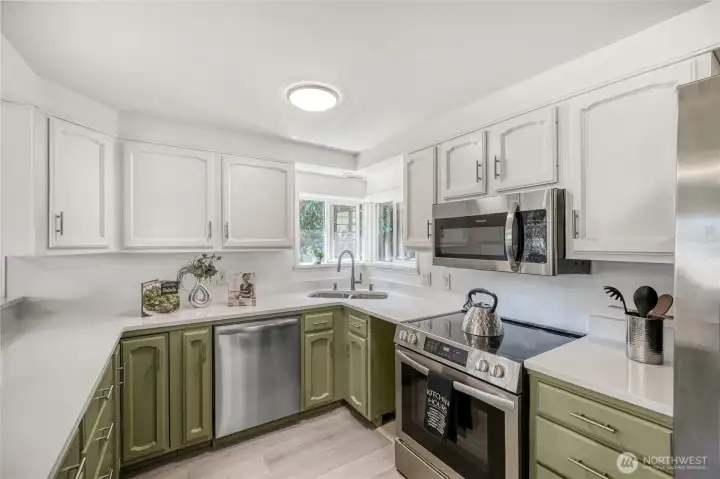 This thoughtfully designed kitchen offers a functional layout that makes cooking and cleanup effortless. The U-shaped design maximizes counter space and storage, keeping everything within easy reach. Bright white upper cabinets and olive-green lowers create a fresh, modern contrast, complemented by durable quartz countertops and stainless-steel appliances. A wide window above the sink fills the space with natural light, while the smooth flow to the dining area and eating bar makes it ideal for everyday use and entertaining alike. This thoughtfully designed kitchen offers a functional layout that makes cooking and cleanup effortless. The U-shaped design maximizes counter space and storage, keeping everything within easy reach. Bright white upper cabinets and olive-green lowers create a fresh, modern contrast, complemented by durable quartz countertops and stainless-steel appliances. A wide window above the sink fills the space with natural light, while the smooth flow to the dining area and eating bar makes it ideal for everyday use and entertaining alike.