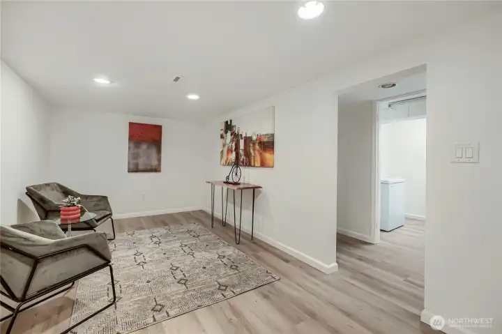 This bright, updated lower-level space offers flexibility for modern living—perfect as a media room, home office, or guest retreat. Recessed lighting and light-toned flooring create a clean, inviting atmosphere, while the open layout allows for easy furniture arrangement. Thoughtful touches like contemporary artwork and neutral finishes make it a comfortable, stylish extension of the home’s living area This bright, updated lower-level space offers flexibility for modern living—perfect as a media room, home office, or guest retreat. Recessed lighting and light-toned flooring create a clean, inviting atmosphere, while the open layout allows for easy furniture arrangement. Thoughtful touches like contemporary artwork and neutral finishes make it a comfortable, stylish extension of the home’s living area