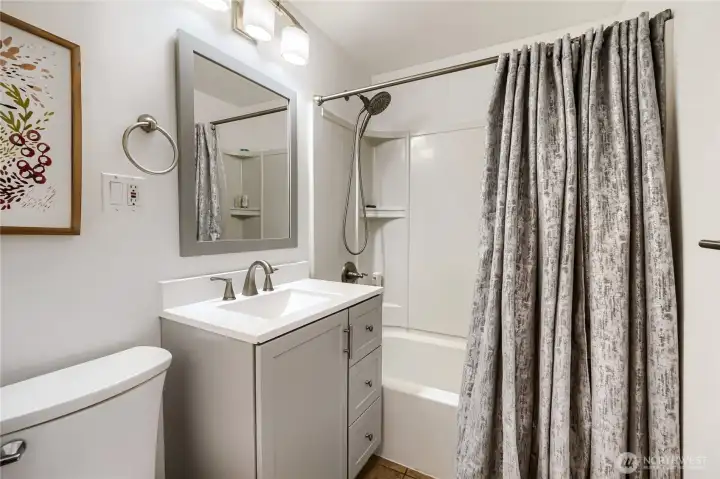 This updated full bathroom features a clean, modern design with neutral tones and quality finishes. A sleek vanity with brushed-nickel fixtures pairs beautifully with the framed mirror and contemporary lighting. The tub and shower combo offers convenience and style, complemented by a textured curtain and built-in shelving for storage. Thoughtfully designed for both function and comfort, this space feels fresh, bright, and ready for everyday use. This updated full bathroom features a clean, modern design with neutral tones and quality finishes. A sleek vanity with brushed-nickel fixtures pairs beautifully with the framed mirror and contemporary lighting. The tub and shower combo offers convenience and style, complemented by a textured curtain and built-in shelving for storage. Thoughtfully designed for both function and comfort, this space feels fresh, bright, and ready for everyday use.