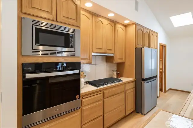 The gourmet kitchen, adorned with floor-to-ceiling custom wood cabinetry, convenient pull-out drawers, sleek stainless-steel appliances, and a gas cooktop make every meal preparation a joy.