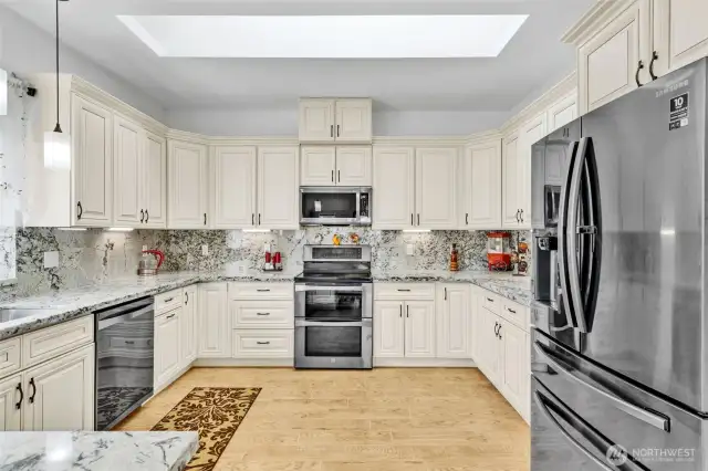 What a kitchen space. Custom cabinetry with soft close doors and drawers. Tile flooring is easy to keep clean. There is so much counter and cabinet space, you may not ever need to use it all!. Thoughtful layout including stainless steel appliances and under cabinet lighting. The skylight creates a wealth of natural light year round. Slab granite counters and backsplash with an undermount sink make clean up a breeze.