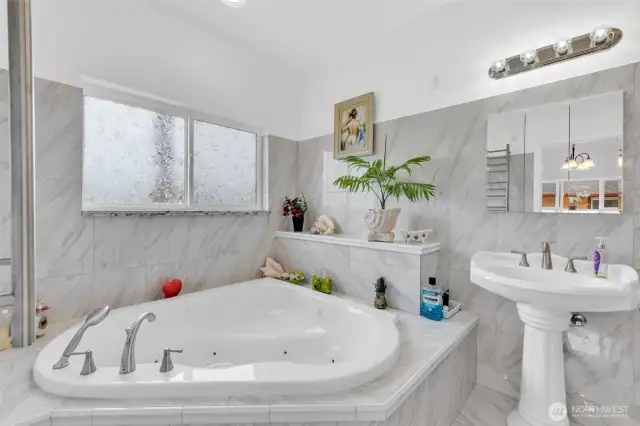 Spa inspired primary bathroom features a Jacuzzi tub. Custom laid tile surrounds you. There is a heated towel rack and walk-in shower to die for.