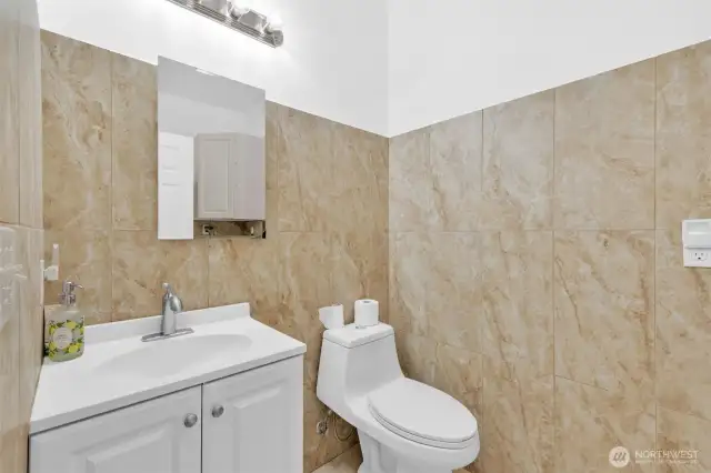 The half bath is just off the main living space. It also has tile floors and tile surrounding the space.