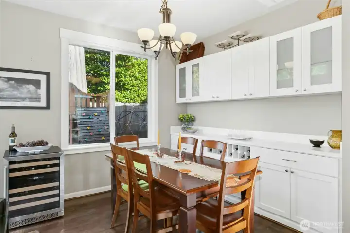 Dining Area:  This bright dining space blends style and practicality with built-in cabinetry and  glass-front storage, ready for entertaining. Sunlight filters through the large window, creating an inviting spot to enjoy a meal or unwind with good conversation.