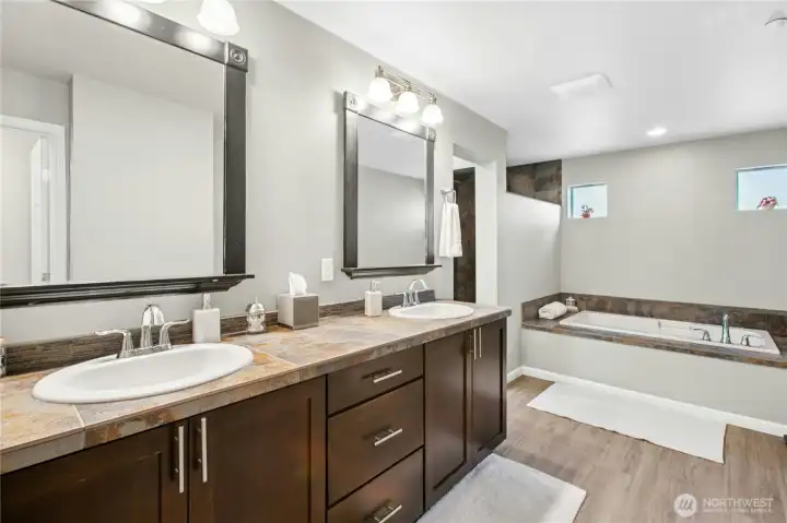 Primary Bathroom:  A touch of everyday luxury — the primary bath offers a deep soaking tub, dual vanities, and warm, natural finishes. Soft light filters through high windows, creating a relaxing and private atmosphere perfect for unwinding at the end of the day.