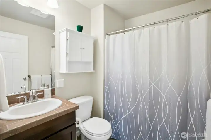Full Bathroom:  Crisp and functional, this full bath features classic tilework, a large mirror, and thoughtful storage. Its simple, neutral palette creates a calm and refreshing space to start or end the day.