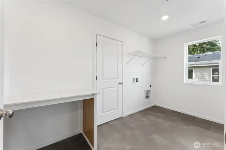 Laundry room features a beautiful quartz folding area. Door connects to primary closet. Laundry room features a beautiful quartz folding area. Door connects to primary closet.