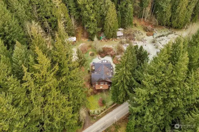 Homestead and gardens shown in clearing.