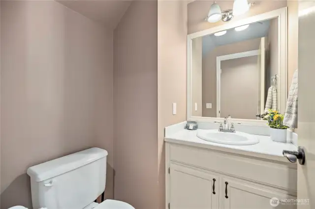 Main floor half bath with updated lighting, neutral tones, and classic white vanity—convenient for guests.