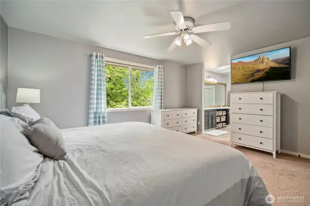 Dual dressers and TV nook lead directly into a luxurious bathroom.