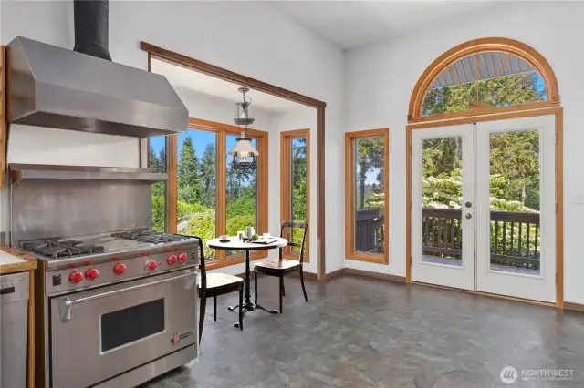 The spacious kitchen has a breakfast nook, Chef's Wolf stove & gas range, and lovely wood casings around the windows.