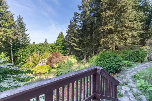 Off the kitchen is a sliding glass door that leads to a small wood deck. Stone pathway leads to the arbor. Note the beautiful flowering tree on the far left.  Beautiful, private and peaceful.