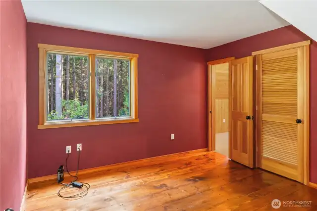 The second guest bedroom with beautiful wide-plank wood floors. There's a walk-in closet on the right. The open door leads to the Bonus room above the garage, which is a pretty cool space.