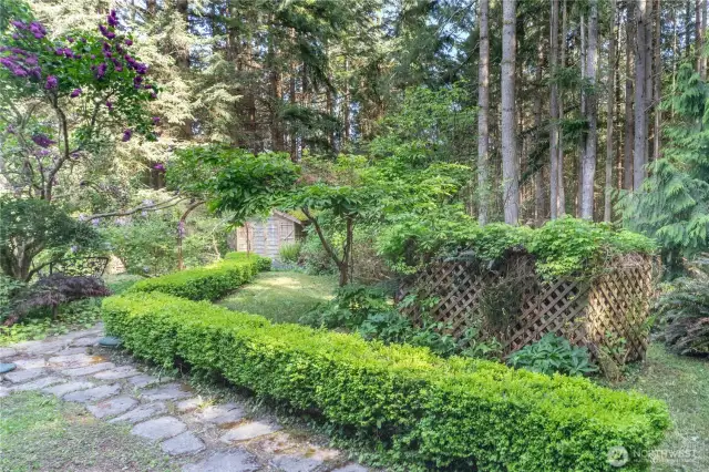 Stone walkways, flowering trees, soaring firs and cedars all add to the beauty of this property. The propane tank is behind the lattice fence on the right.